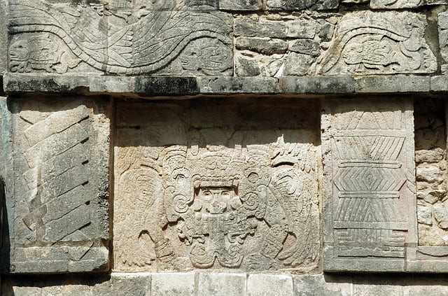 Engravings of god figures in the stone walls of Mayan structures.