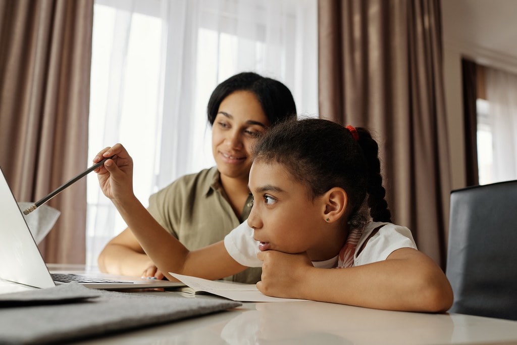 Mum and daughter sat at table learning about Anglo-Saxon crime and punishment on a laptop.