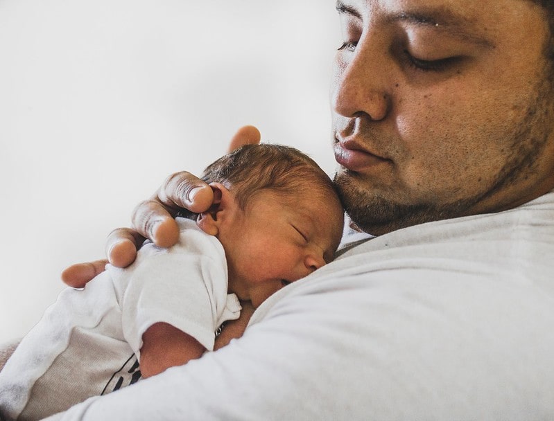 Tiny newborn baby girl sleeping on her dad's chest.