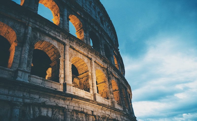 The Colosseum lit up in the evening, built out of concrete, a Roman invention.