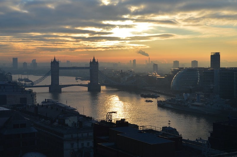 View of Tower Bridge and the Thames riverbank at dawn.