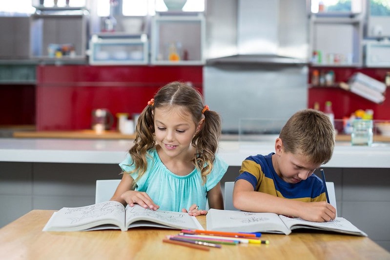 Little girl and boy sat at the kitchen table studying about Iron Age weapons.