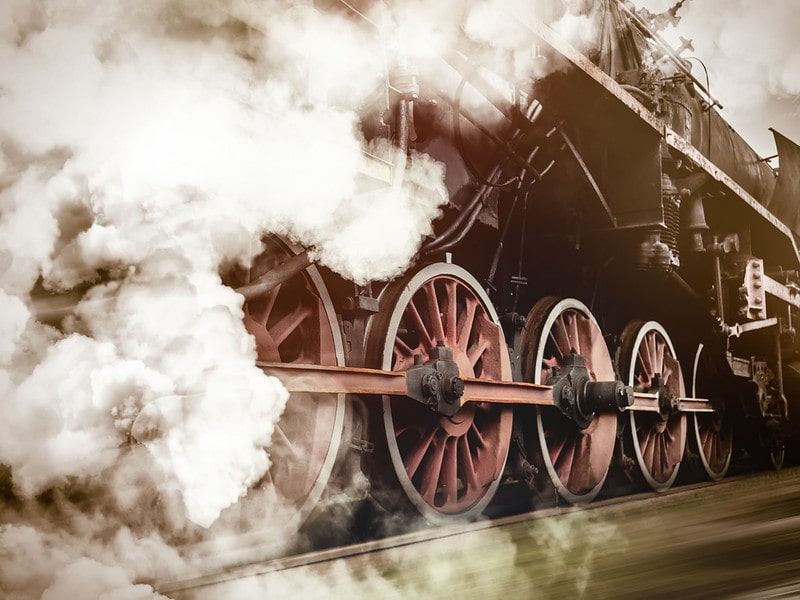 Close up of the wheels of a moving Victorian steam train.