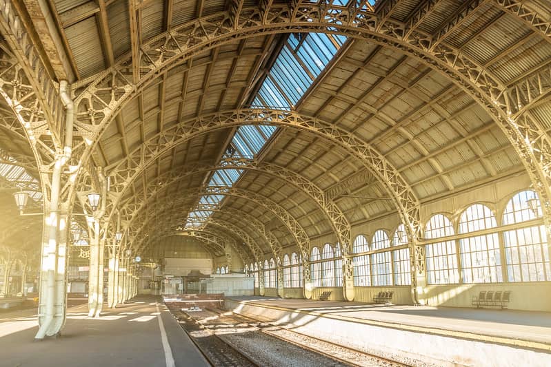 The platforms and tracks of an empty train station with an arched roof.