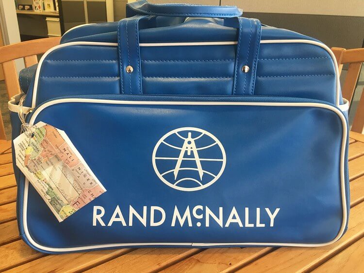 DIY luggage ta made from a printed map tied onto a blue carry-on bag.