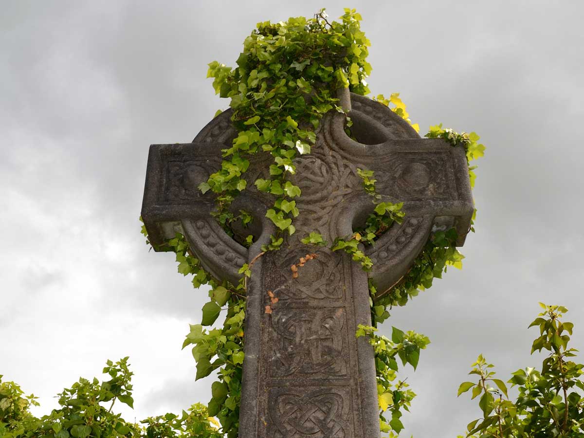 A Celtic stone monument with ivy growing over it.