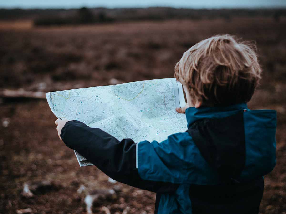 Young boy holding up a map trying to read it.