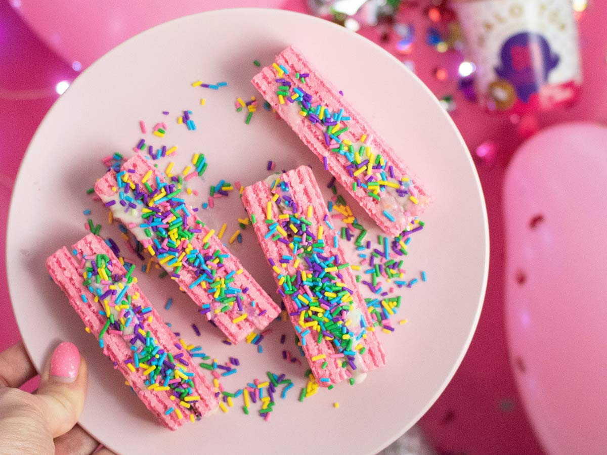 Pink cake slices on a plate, decorated with colourful sprinkles.