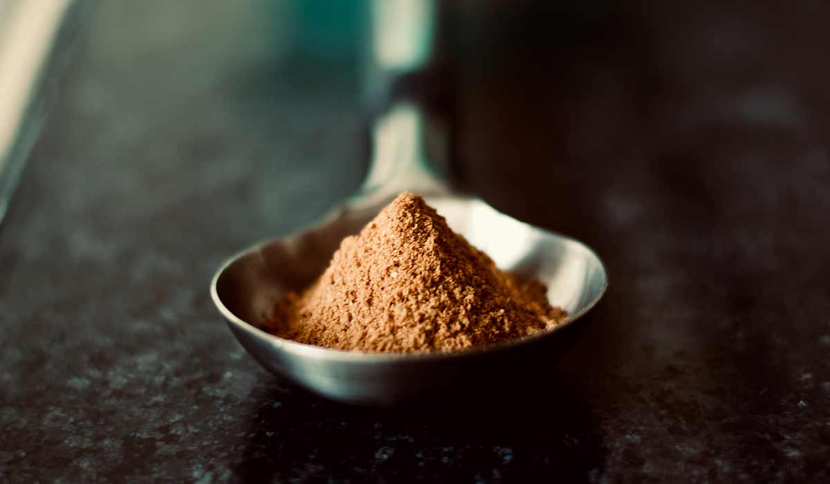 A silver spoon with a pile of brown sugar in it.