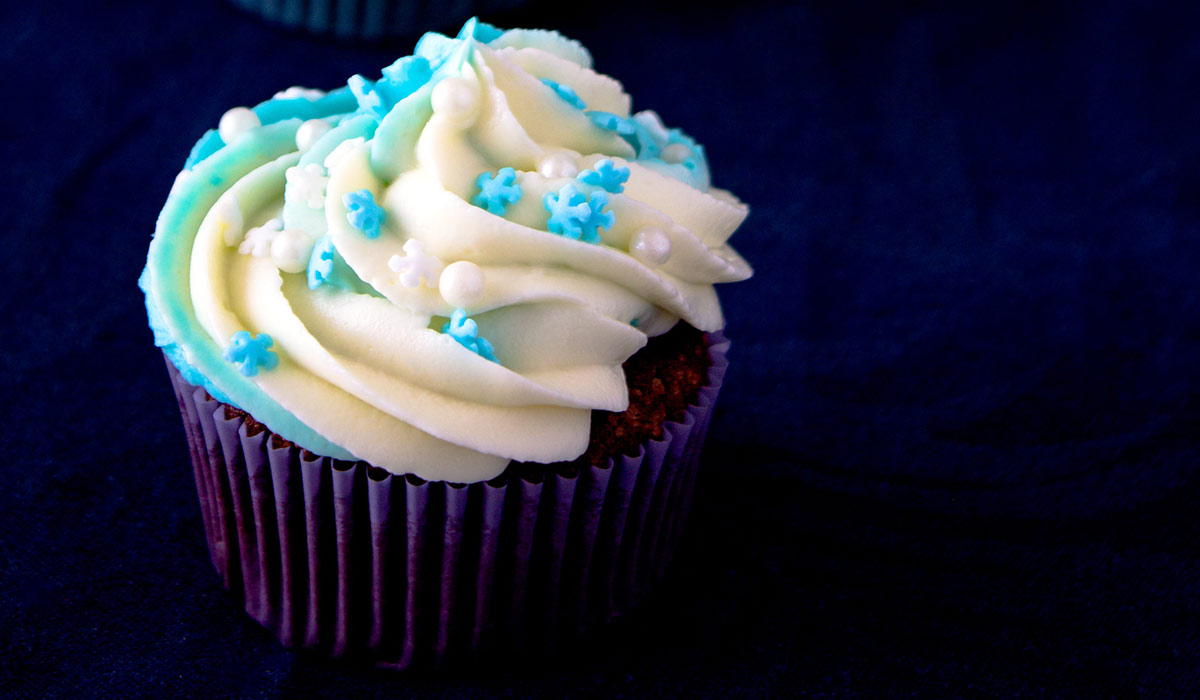 Chocolate cupcake with blue star sprinkles on the white frosting.