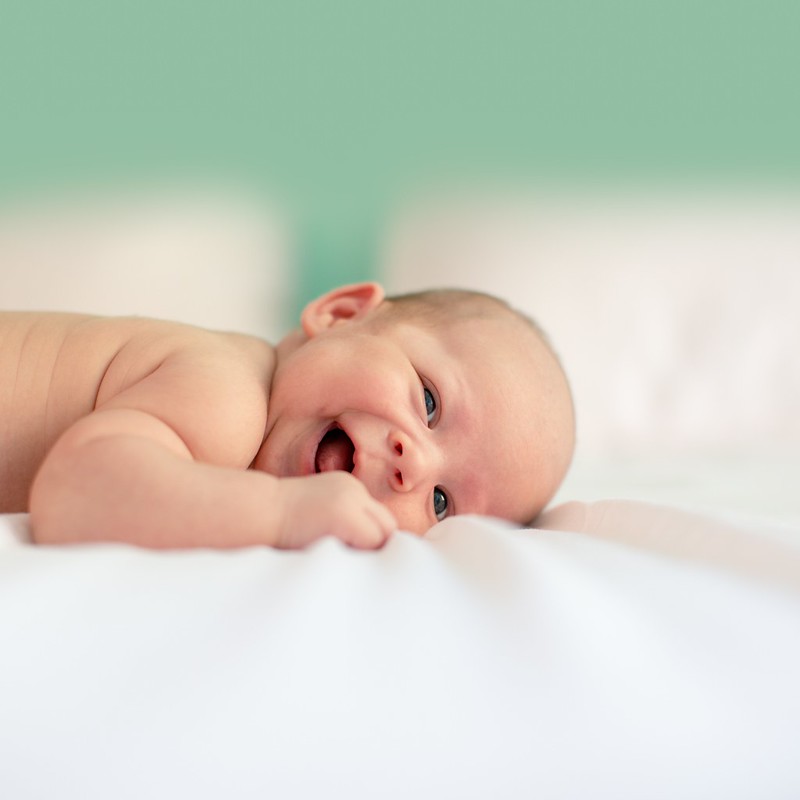 Happy baby lying on its tummy smiling.