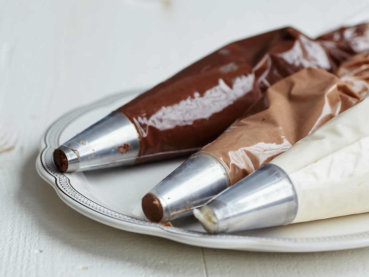 Three piping bags of chocolate and vanilla frosting.