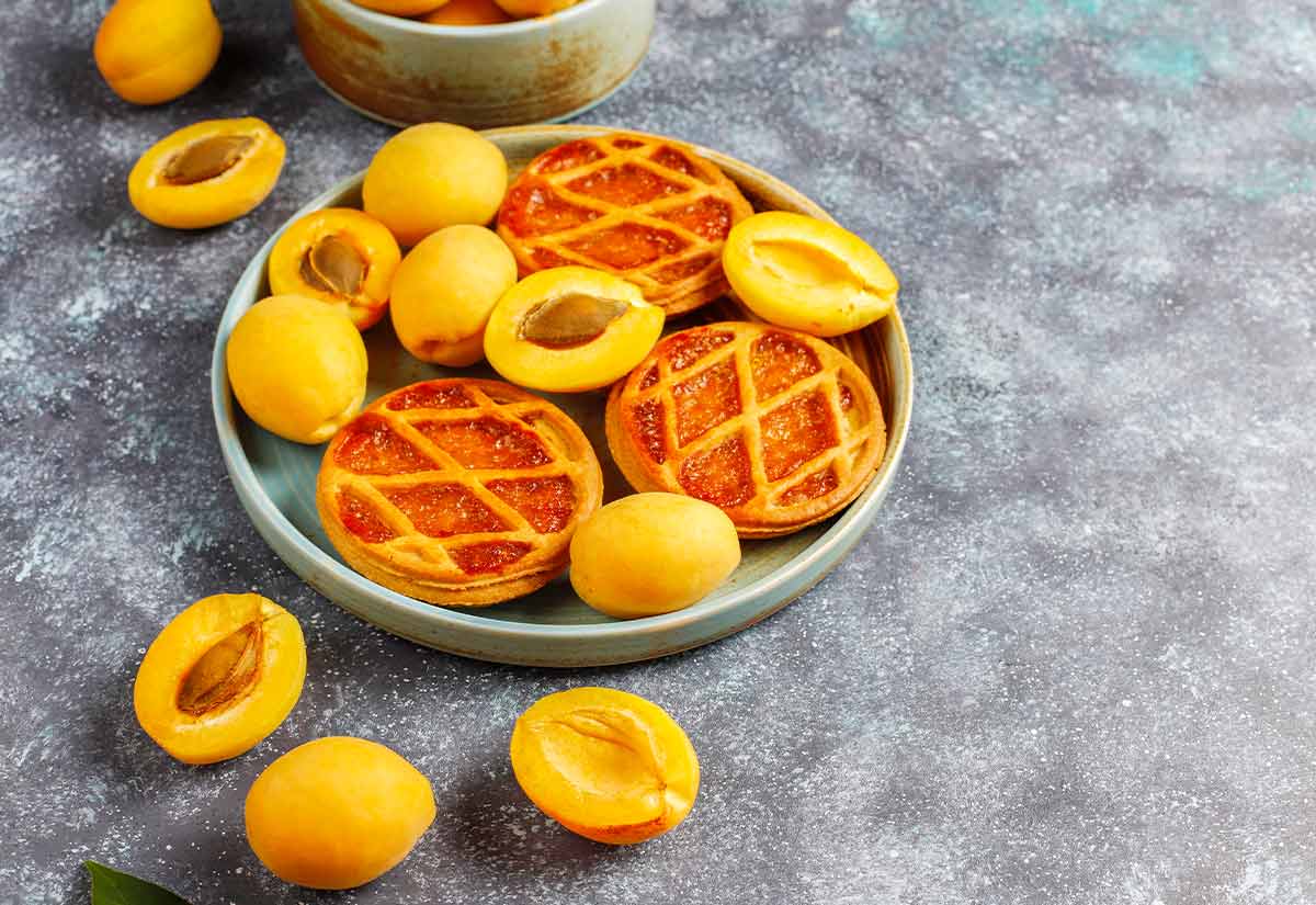 Apricot jam tarts and apricots cut in half.