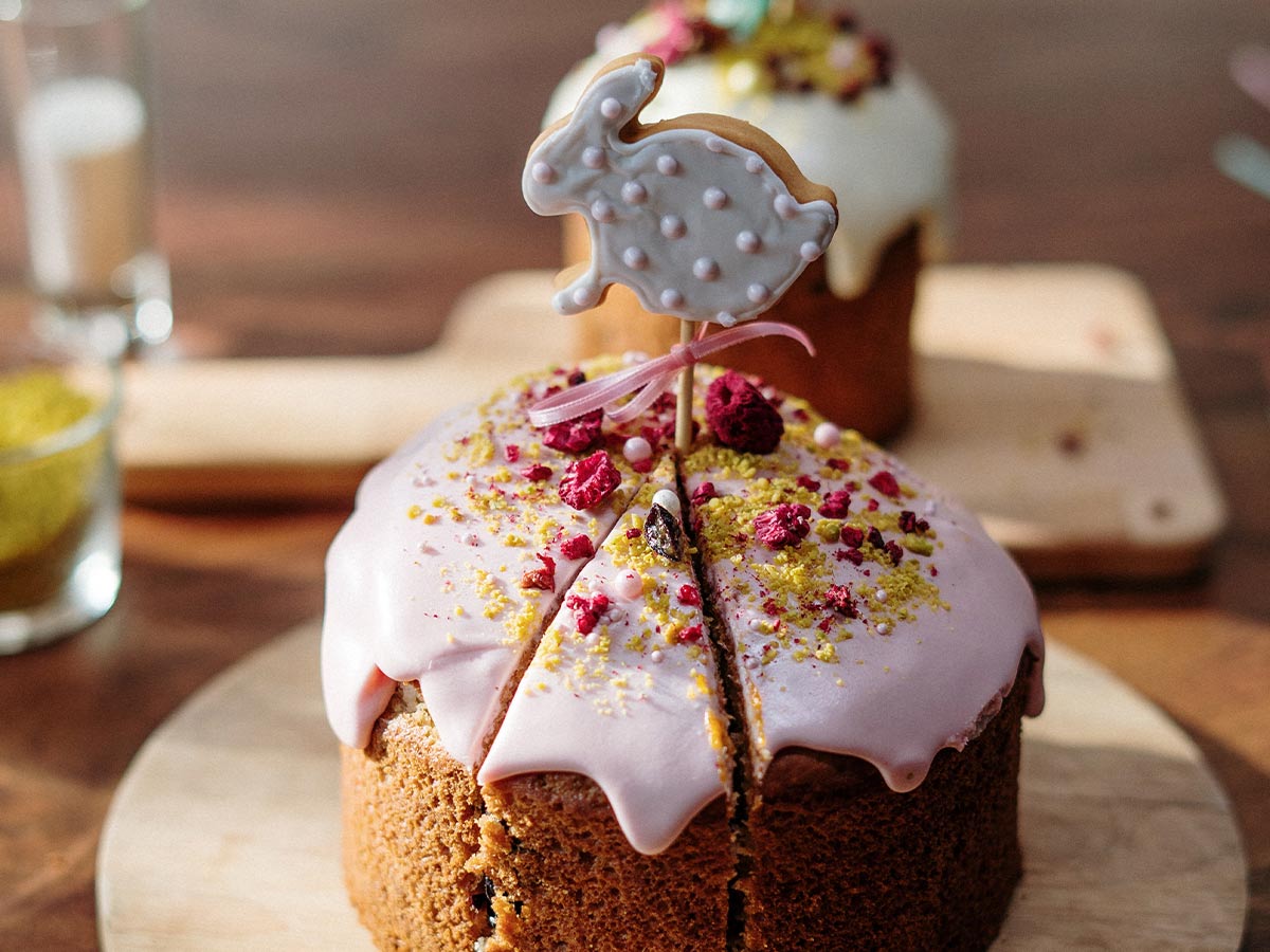 Cake with pink icing and a biscuit shaped like a rabbit stuck on a stick on top.