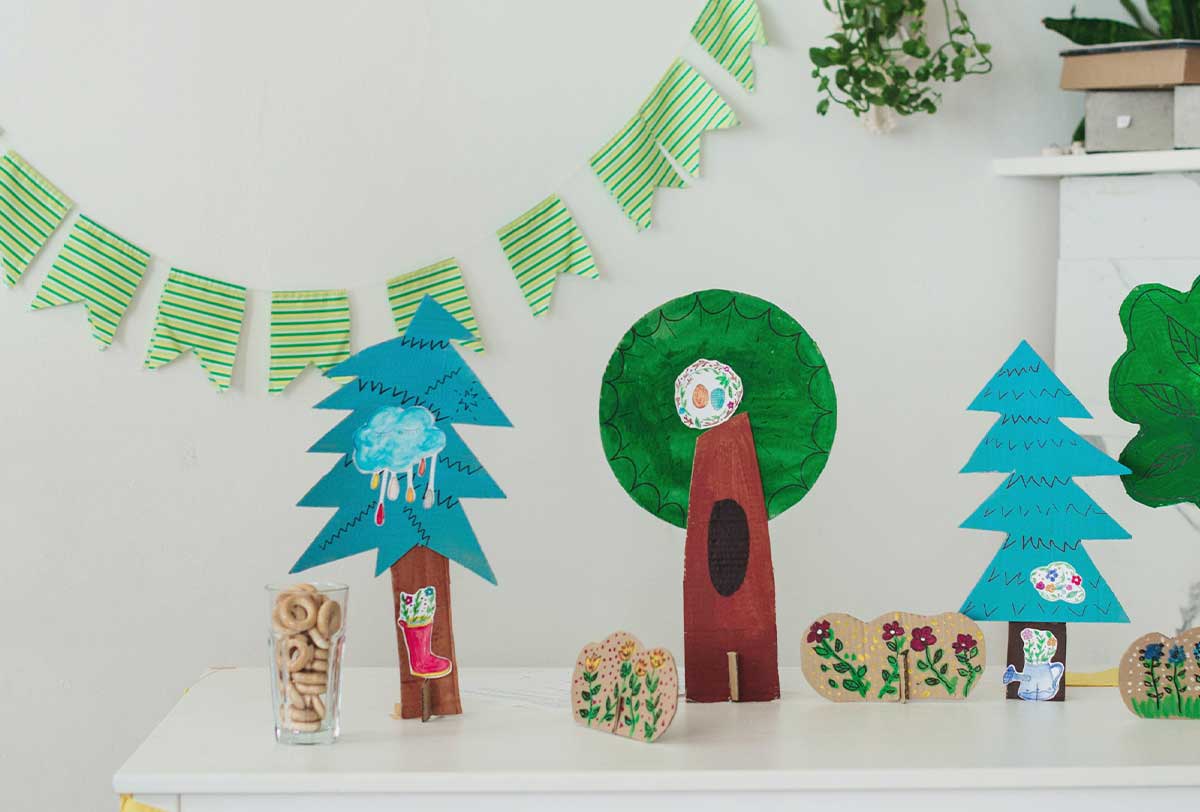 Green bunting birthday banner hanging on the wall behind a table with crafts made by the kids.