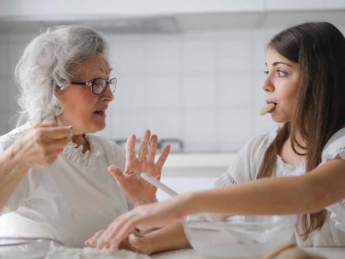 Grandma and grandchild sat in the kitchen talking while baking.