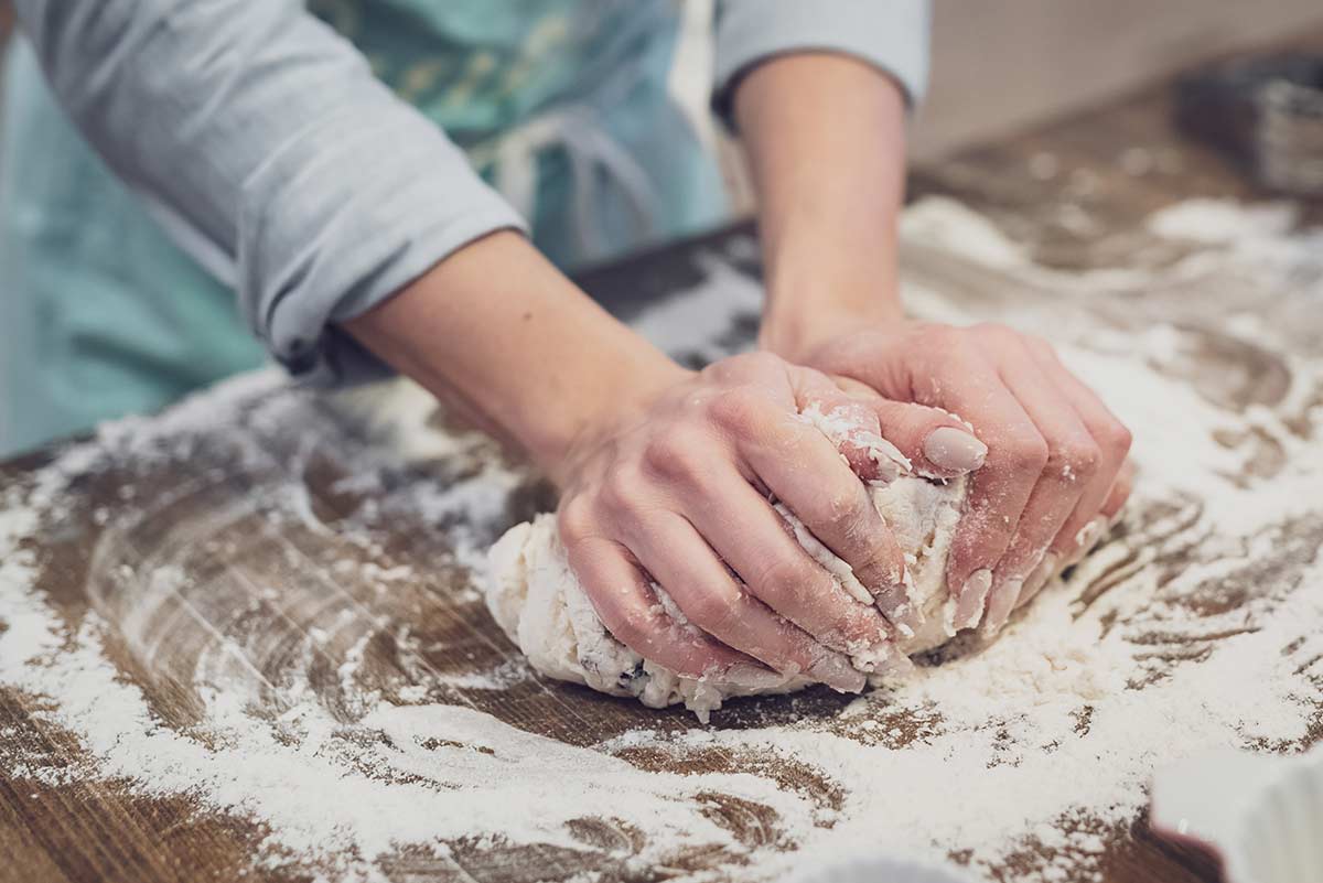 Close up of a woman kneading dough on the kitchen worktop.