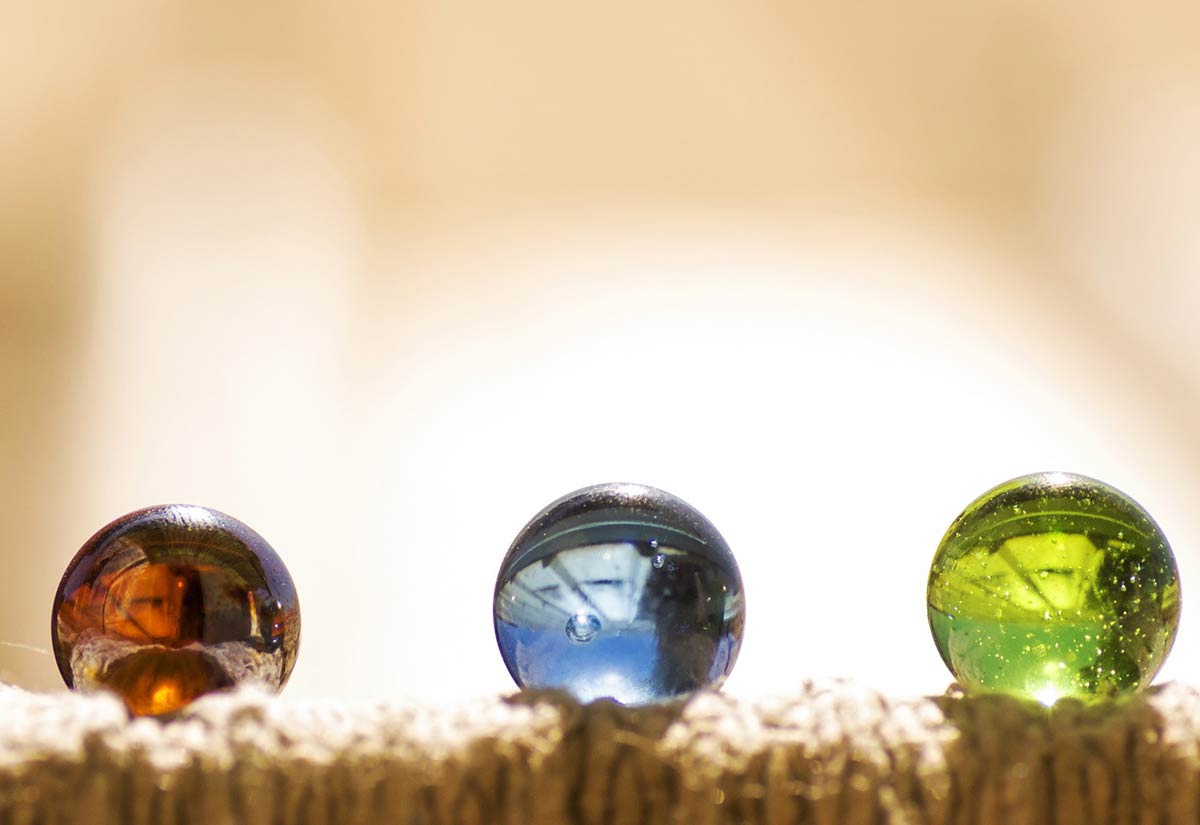 A red, green and blue marble all on the carpet in a line.