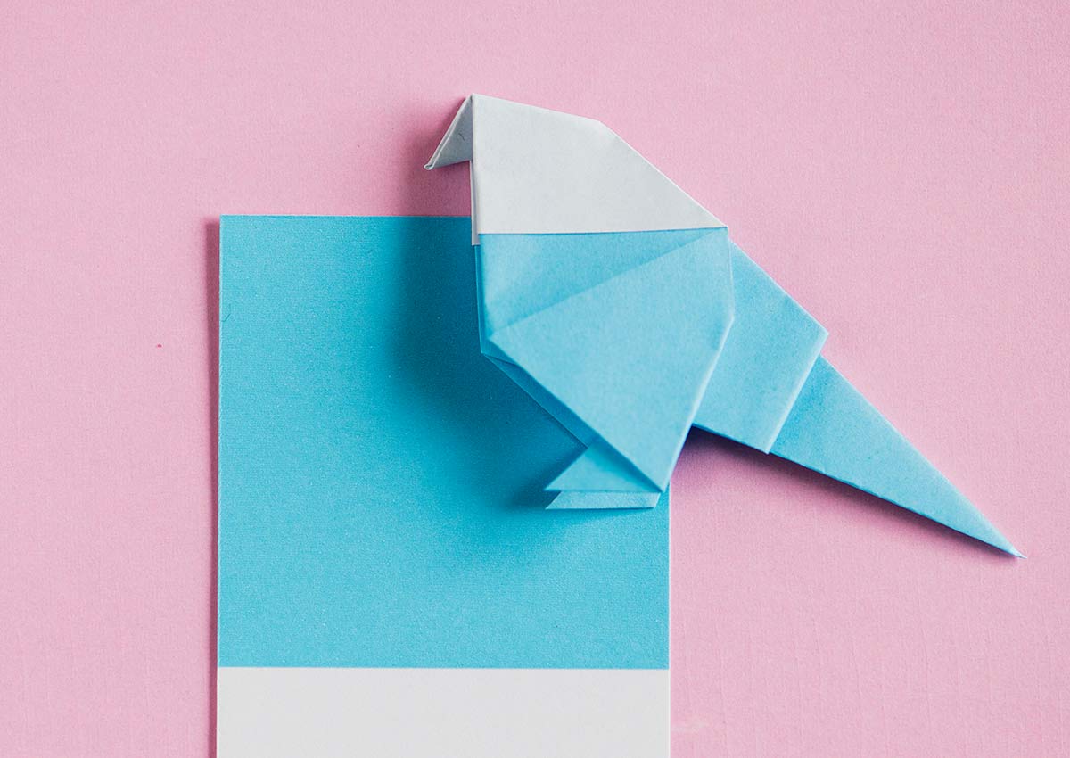 Blue and white origami robin against a light pink background.