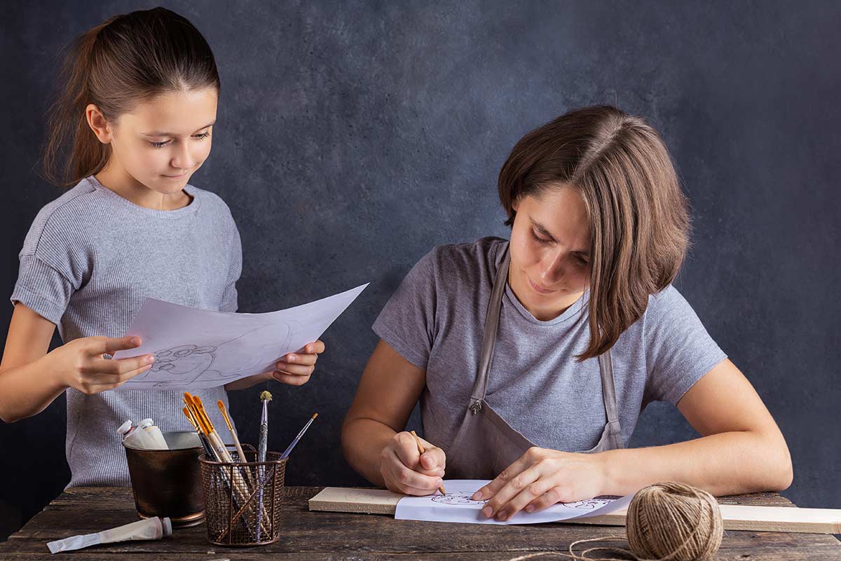 Mum and daughter looking at drawings of their plan for a robot toy.