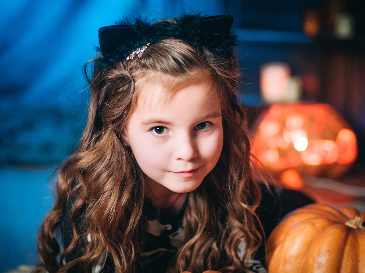 Young girl wearing black cat ears.