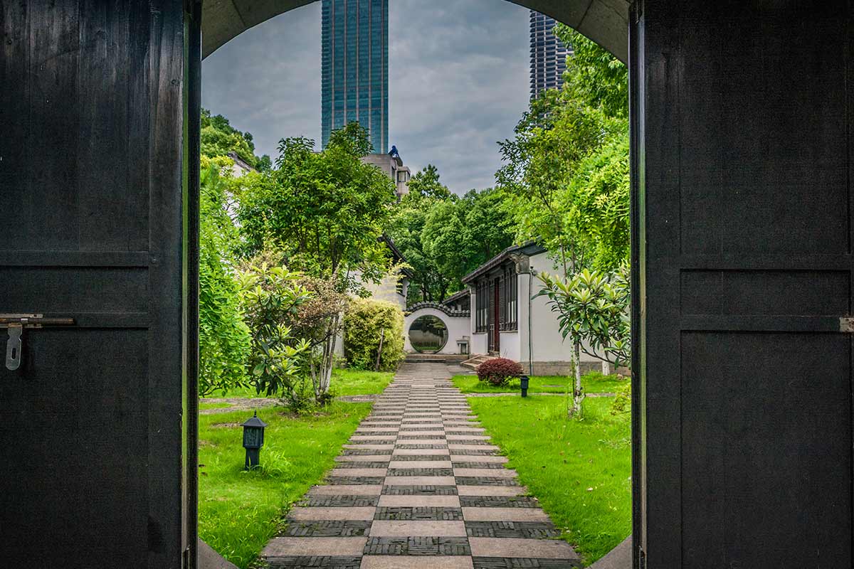 View of a Chinese landscape through double doors, skyscrapers in the background.