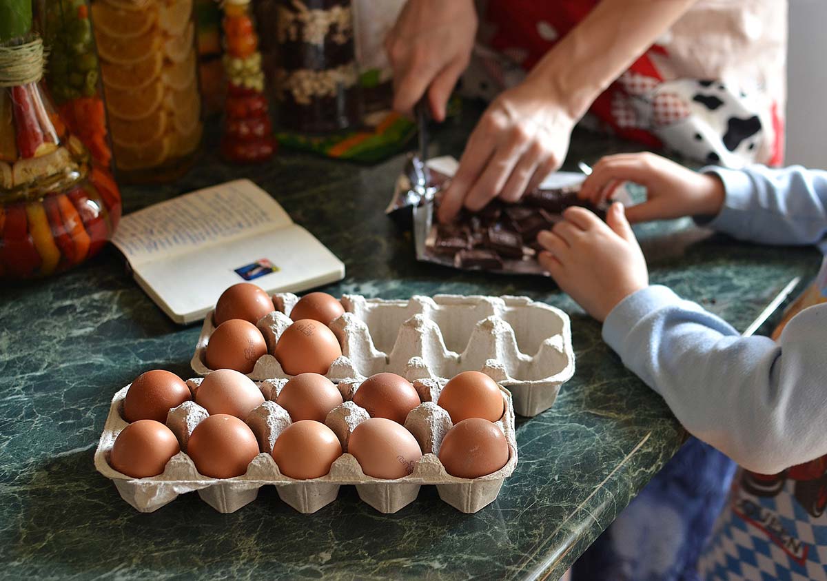 Close up of child cracking eggs into a bowl to make a football pitch cake.