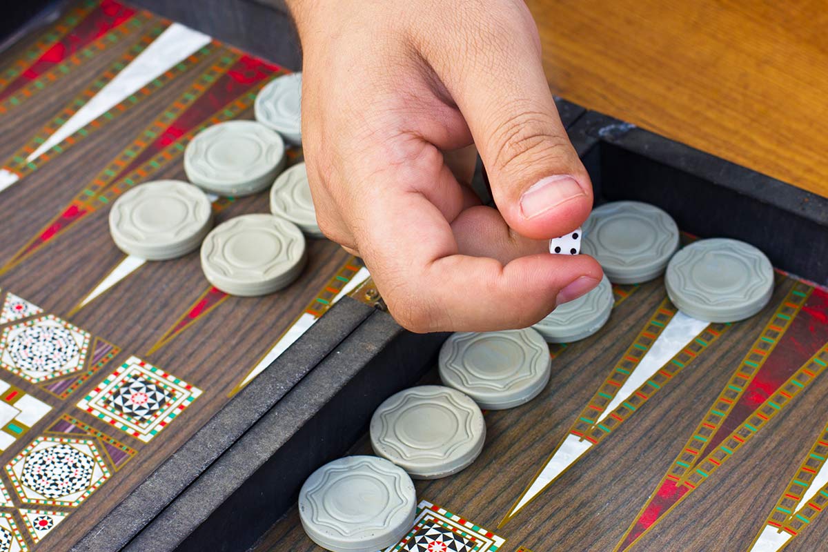 Hand reaching for a checker on the backgammon board.