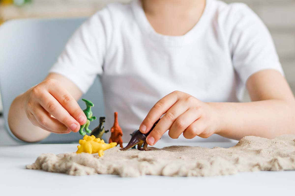 Young boy playing with dinosaur toys which he can use when making his own key ring.