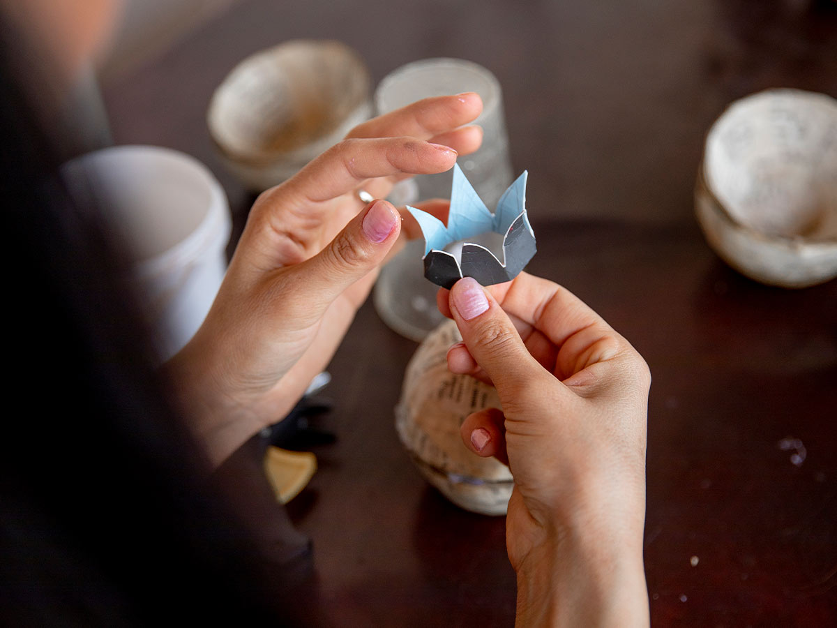 Close up of a woman holding a flower she made from paper to put on her DIY flower wreath.
