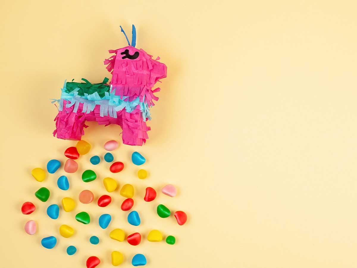 A colourful unicorn pinata arranged with colourful sweets falling out of it.