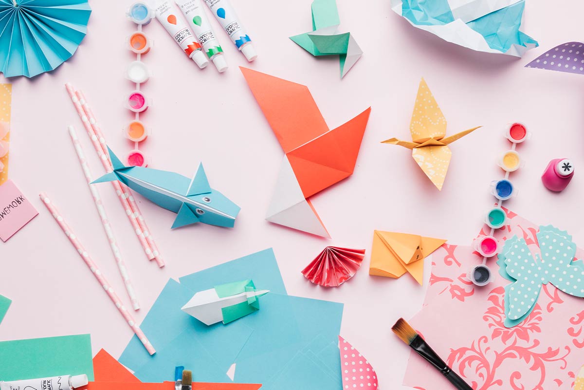 Various origami animals and shapes, already made, places on a pink surface.