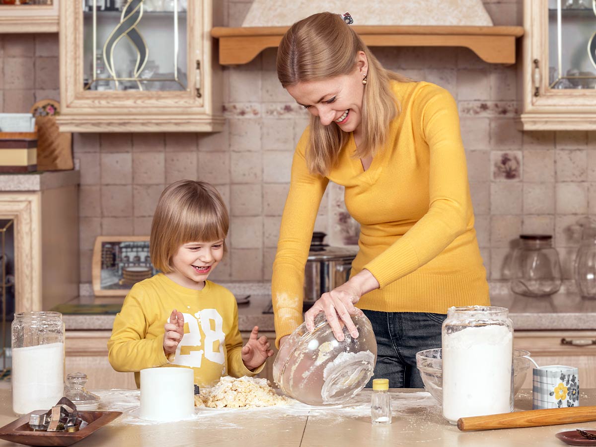 Mother and son in the kitchen together baking a ladybird cake.