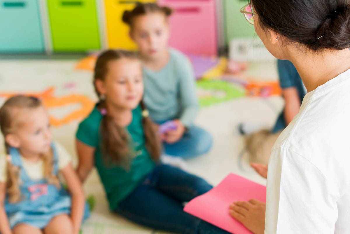 Female teacher teaching young girls how to tell time in the classroom.