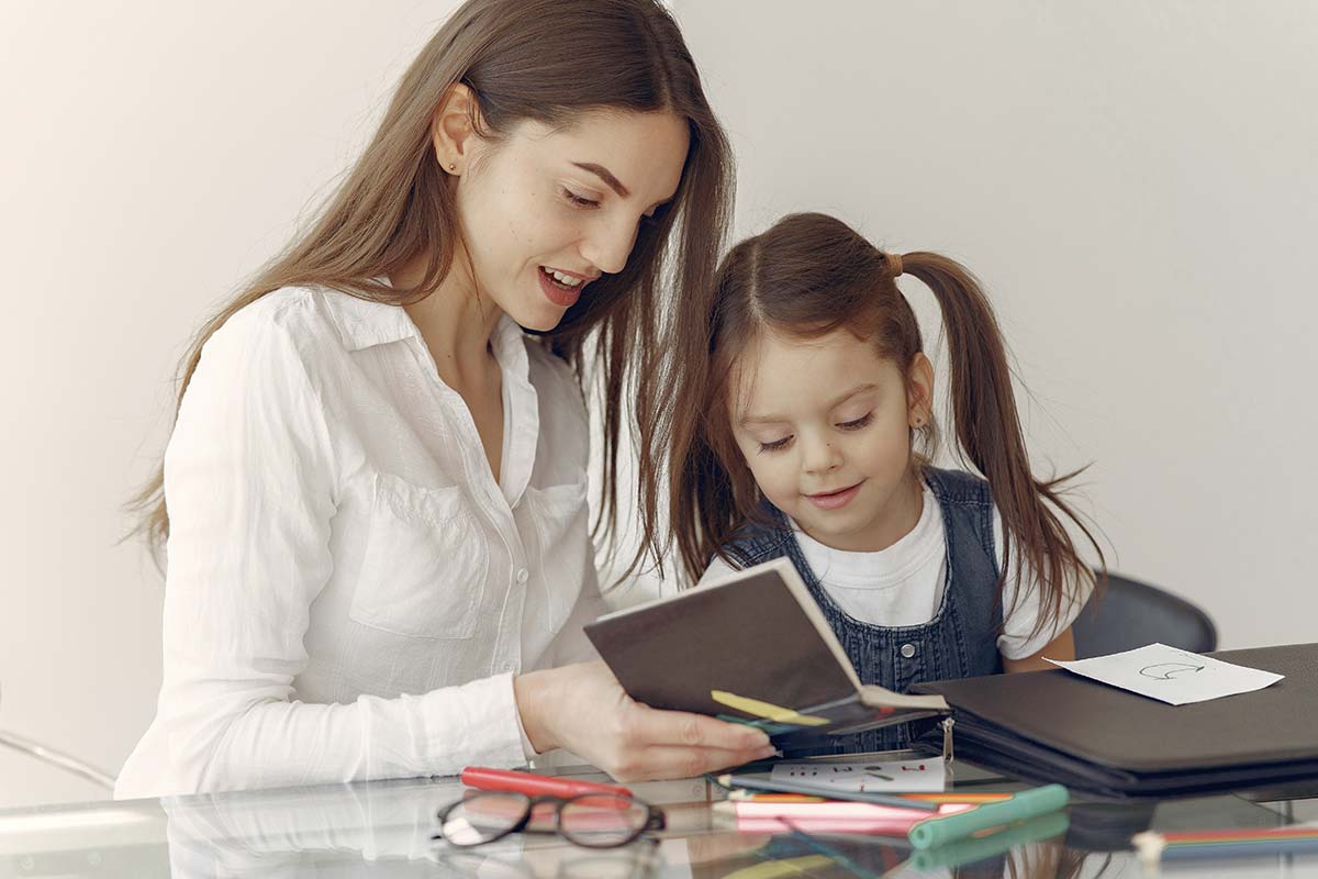A mother and daughter sitting together looking in a notebook at her DIY reward chart.
