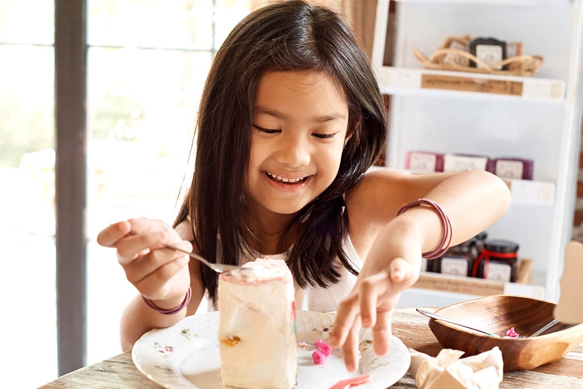 Young girl eating a large slice of birthday cake.