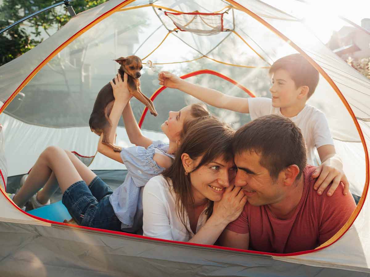 Happy family lying in their camping tent together with their dog.