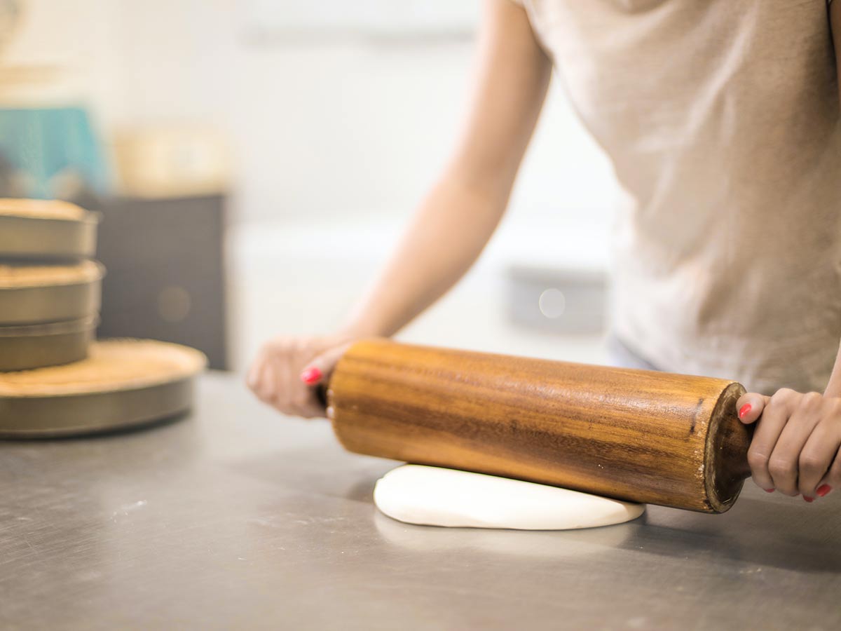 Close up image of someone using a large rolling pin to prepare icing for a digger cake.