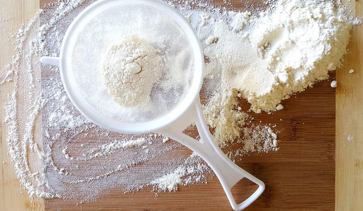 A close up image of a sieve filled with flour, one of the ingredients in the giant cupcake recipe.