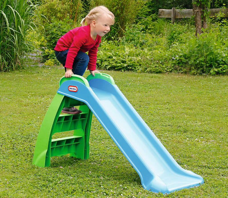 Child about to go down a blue and green garden slide.