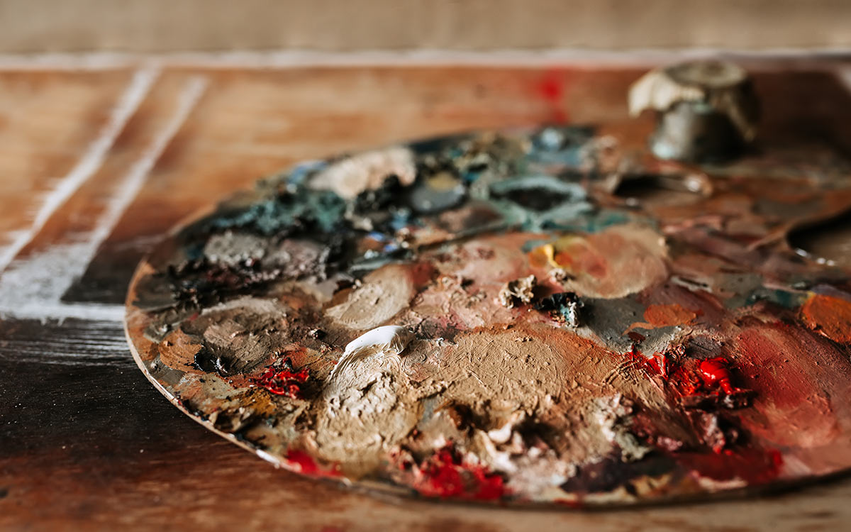 A wooden artist's palette covered in paint, representing the materials used in WW2 art.