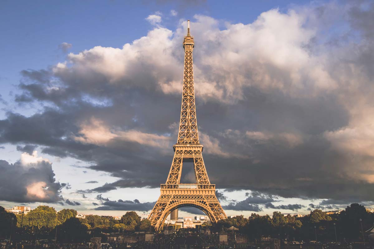 The Eiffel Tower in Paris with a cloudy sky behind it.