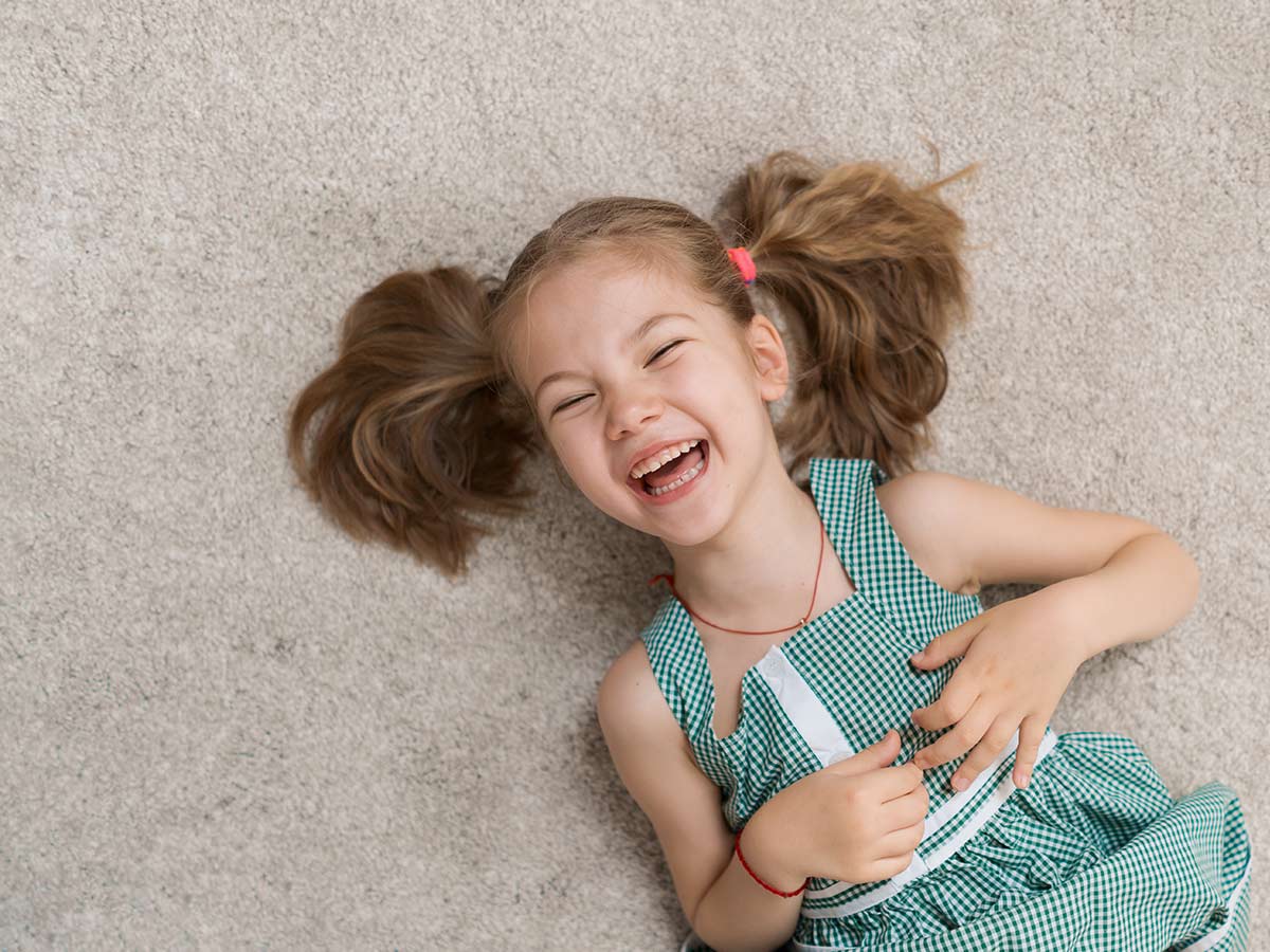 Young girl lying on the floor on her back laughing at deer puns.