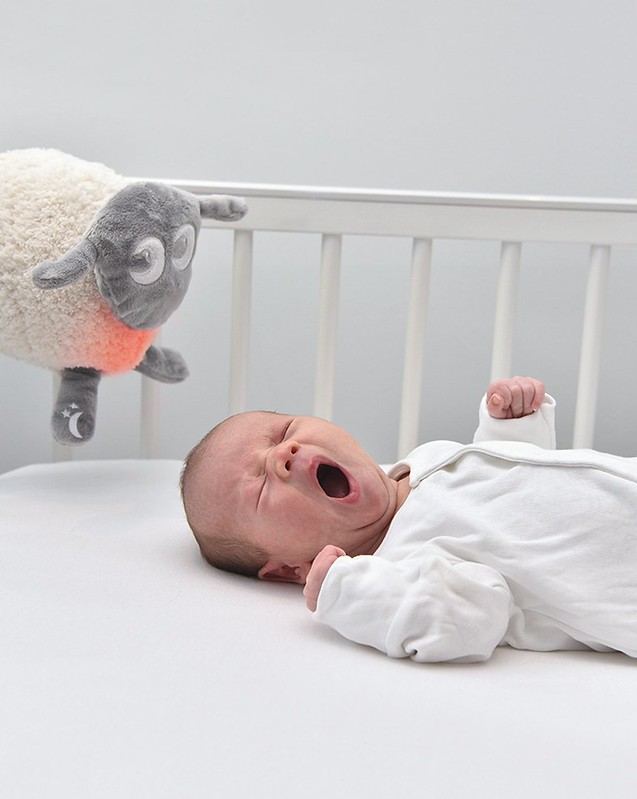 Baby sleeping in a cot with Ewan Dream Sheep Deluxe.