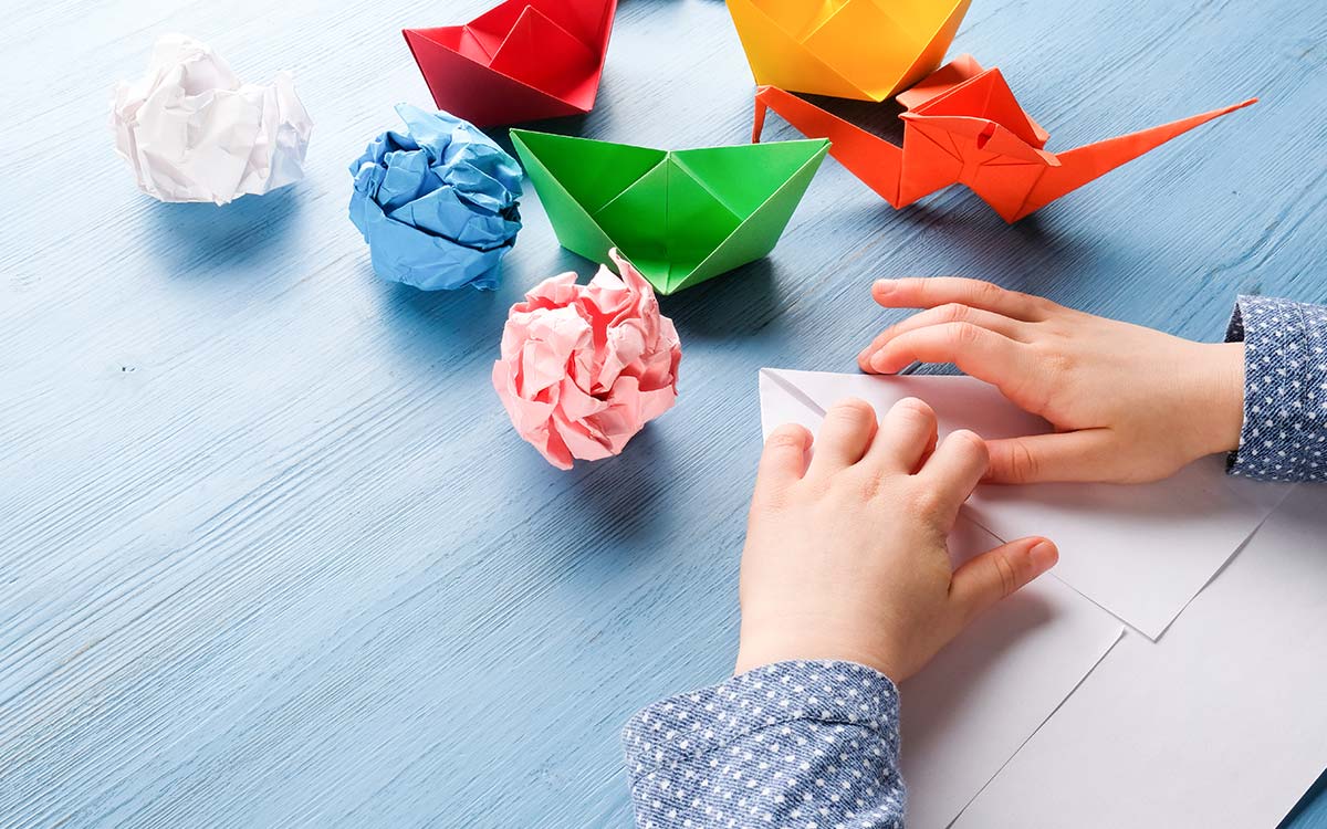 Close up of hands folding paper making origami animals.
