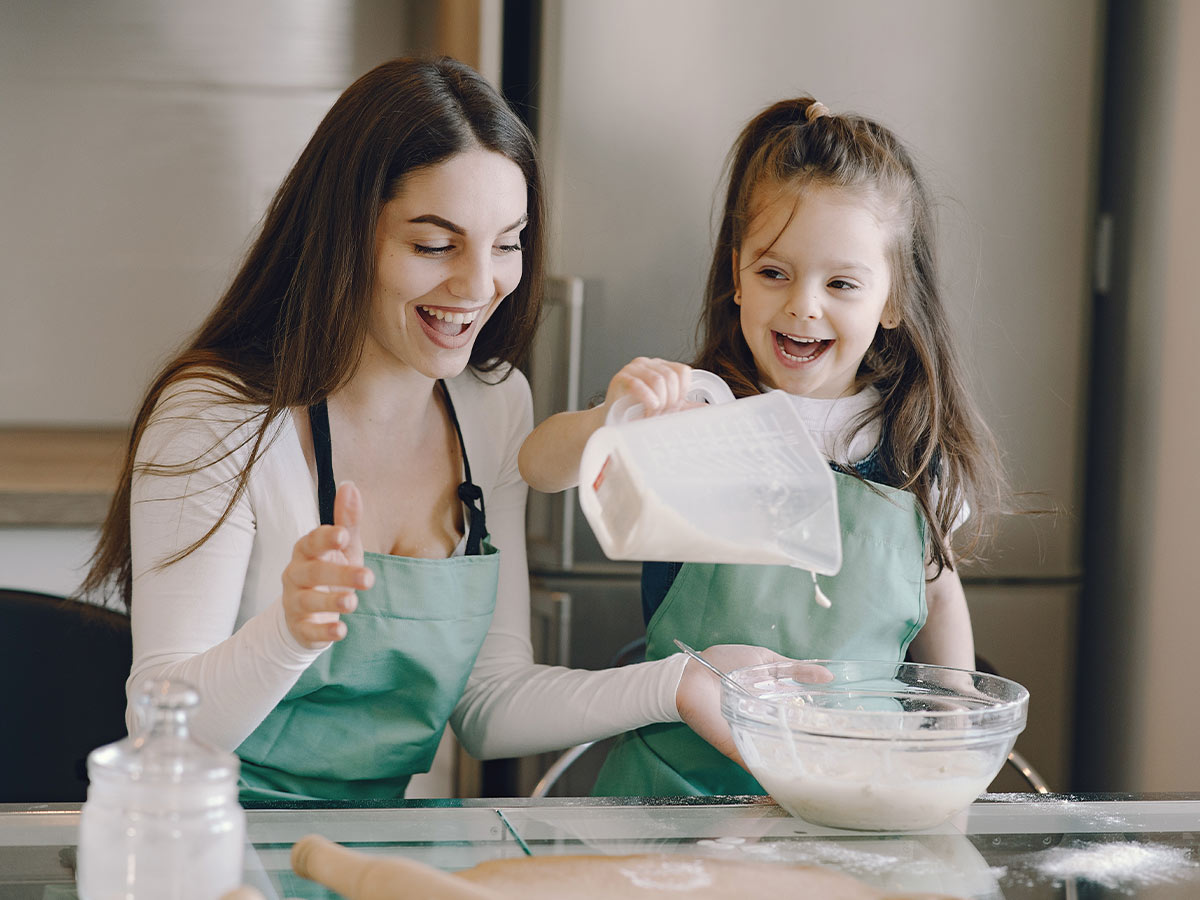 Mum and daughter in the kitchen adding the ingredients to the Peppa Pig cake batter.