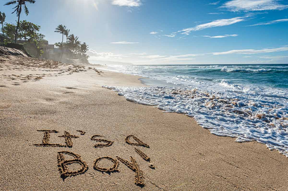 'It's a boy' written in the sand on the beach in Hawaii.
