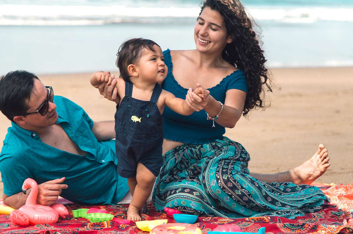 Parents sat on a rug in the sand on the Hawaiian beach playing with their baby boy.