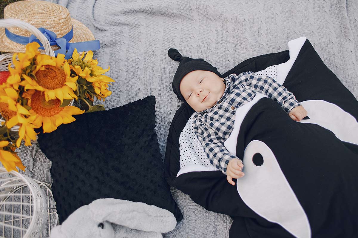 Baby boy lying on his back wrapped in an Orca whale blanket.