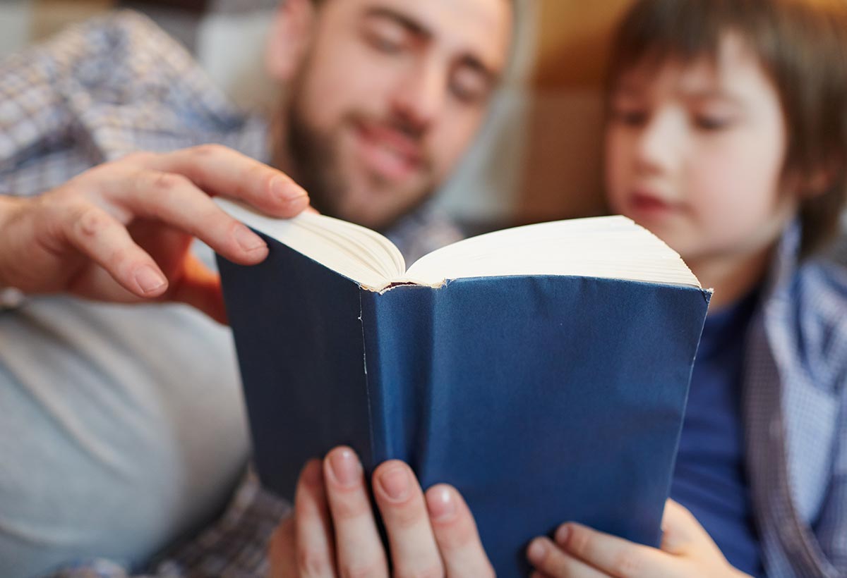 Dad and son reading a book together to see examples of the passive voice in writing.